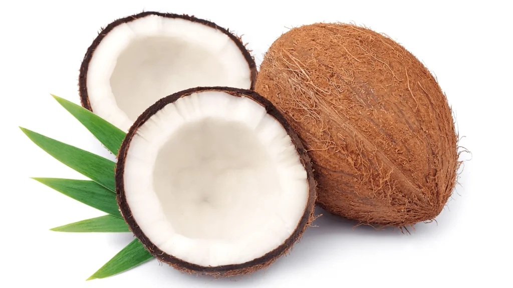 Image d'une noix de coco entière et de deux moitiés ouvertes montrant leur chair blanche, accompagnées de feuilles vertes pour une ambiance tropicale.